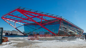 一幢大型建筑的施工照片，上面有红色的桁架